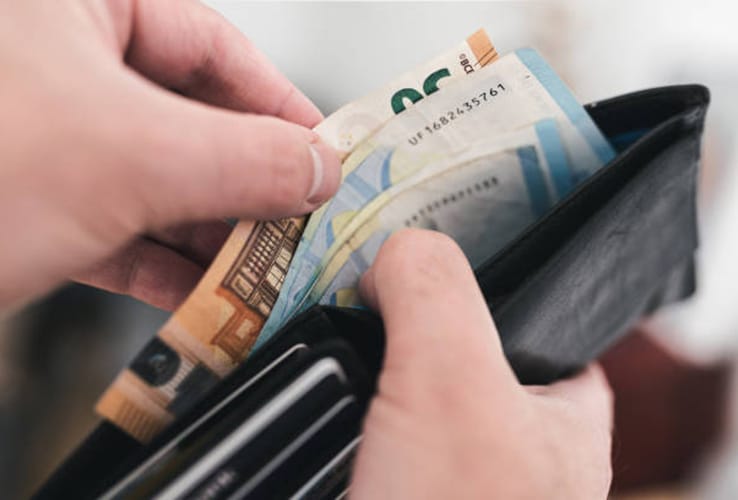 Close up view of hands taking money out of a wallet, spending cash concept