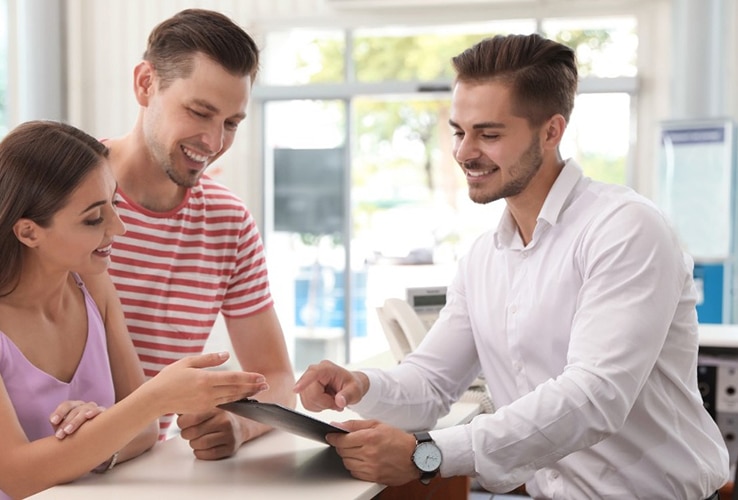 Salesman consulting young couple in car salon