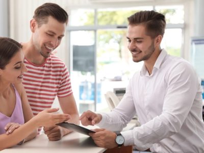 Salesman consulting young couple in car salon